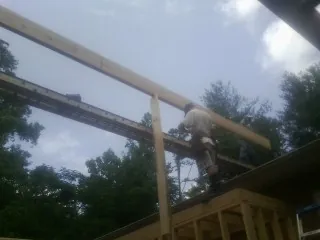 Carpenter setting a ridge beam over a new addition frame — Ice Dam Removal by Roofing Brothers in Enterprise